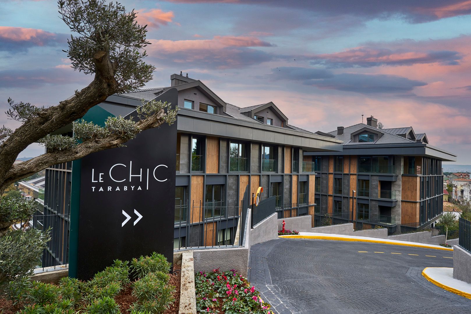 Le Chic Tarabya site girişi, gün batımında ahşap ve antrasit cepheli bloklar
