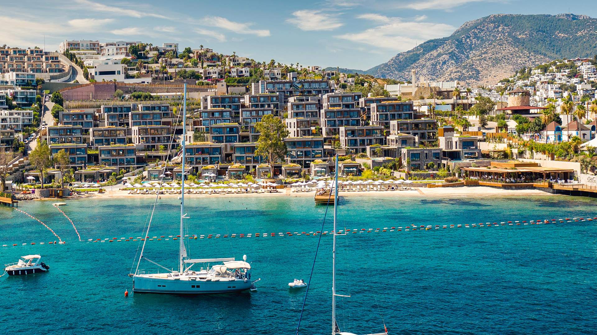 Asarlık koyunda Le Chic Bodrum; denizde yelkenli, arkada kademeli bloklar